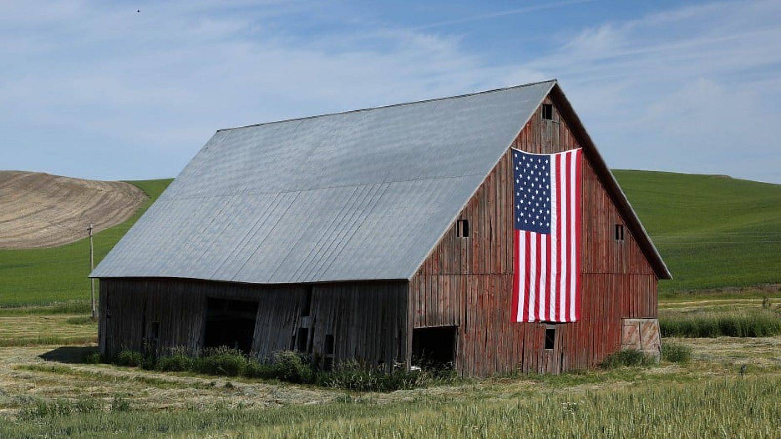 A barn with an American flag on it in rural America.