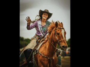 A rodeo queen riding a a horse in the arena.