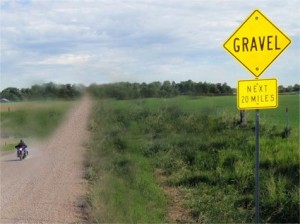 A motorcycle travels on a gravel road.