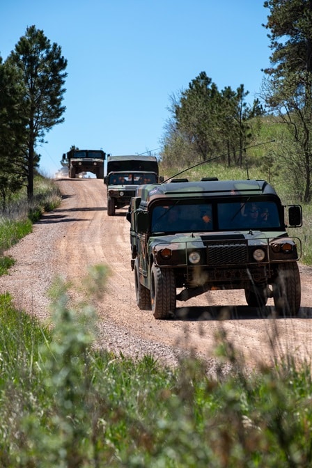 Military vehicles travel down a gravel road