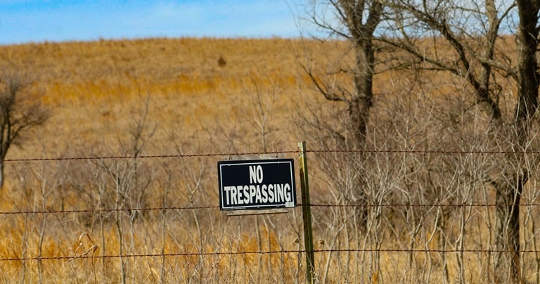 A no trespassing sign hangs on a fence