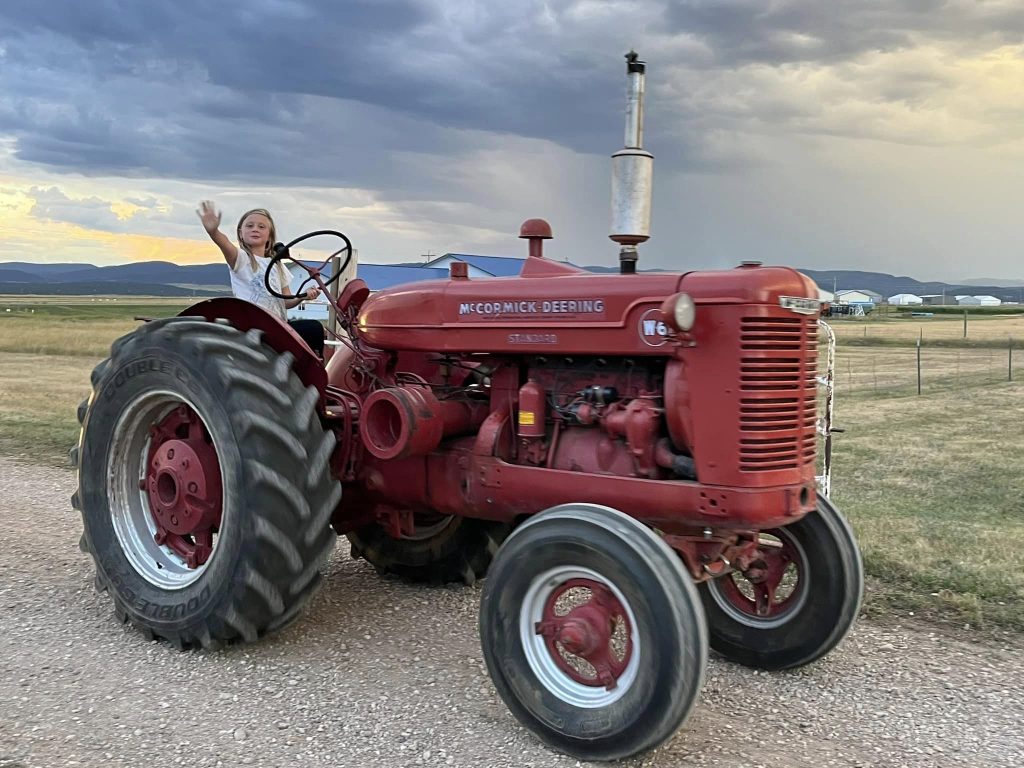 A girl drives an antique farm tractor