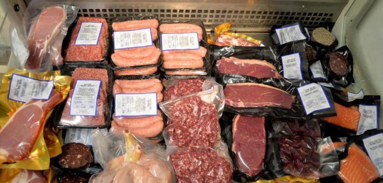 A variety of fresh meats in a meat case.