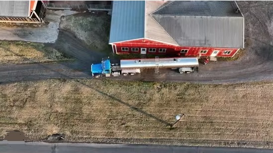 A milk tanker trucker parked next to a barn